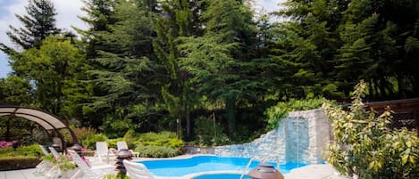 Une piscine avec des chaises longues et des plantes en pot.