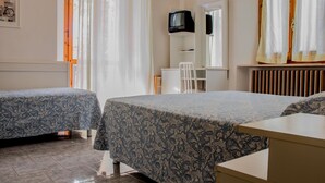 Un dormitorio con dos camas, un escritorio, una silla, un televisor y una ventana con cortinas.