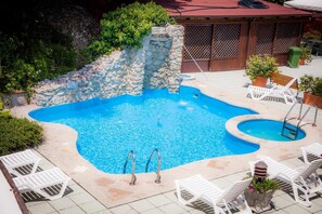 A swimming pool with a stone wall and a wooden fence in the background. - Hotel Ulisse (Carpegna)