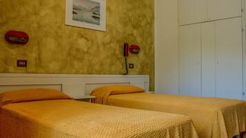 Una camera d'albergo con due letti, un quadro appeso alla parete e un telefono sul comodino.
