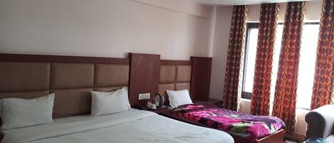 Habitación de hotel con dos camas, un ventilador de techo y cortinas estampadas.
