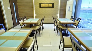 A conference room with a long table and chairs, a wall-mounted artwork, and a view through a large window.