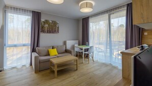 Una habitación moderna y luminosa con sofá, una mesa de centro, una mesa de comedor con sillas y una zona de cocina.