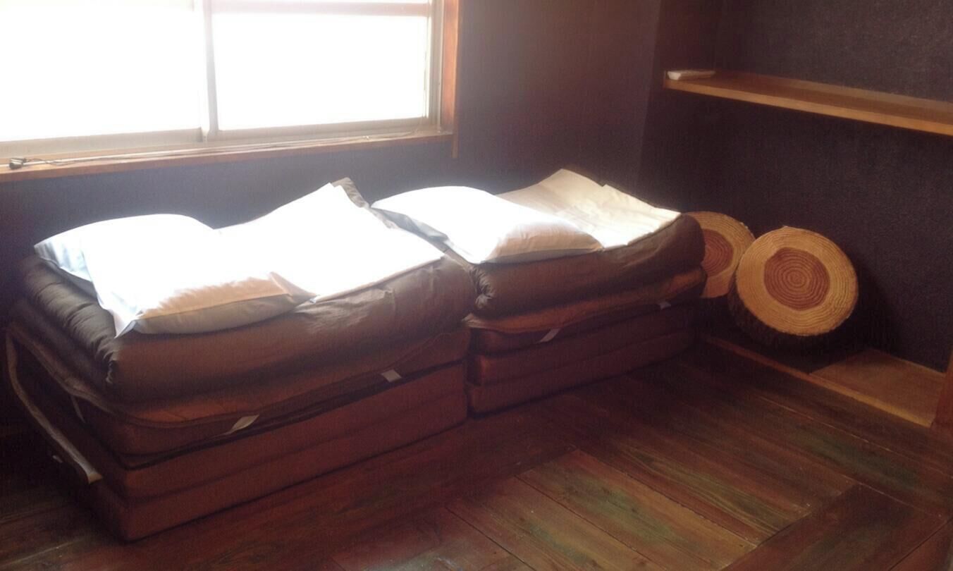 A room with a bed, a window, and a wooden shelf.