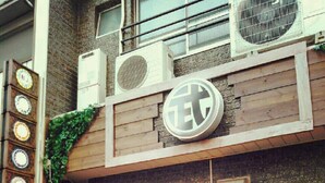A building with a wooden facade, a circular logo, and a sign indicating a station. - Takamatsu Guesthouse BJ Station (Takamatsu)