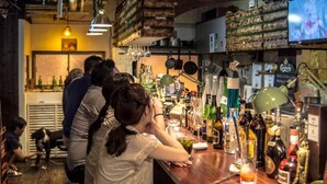 A bar area with a variety of bottles and glasses, a television screen, and a rustic interior design. - Takamatsu Guesthouse BJ Station (Takamatsu)