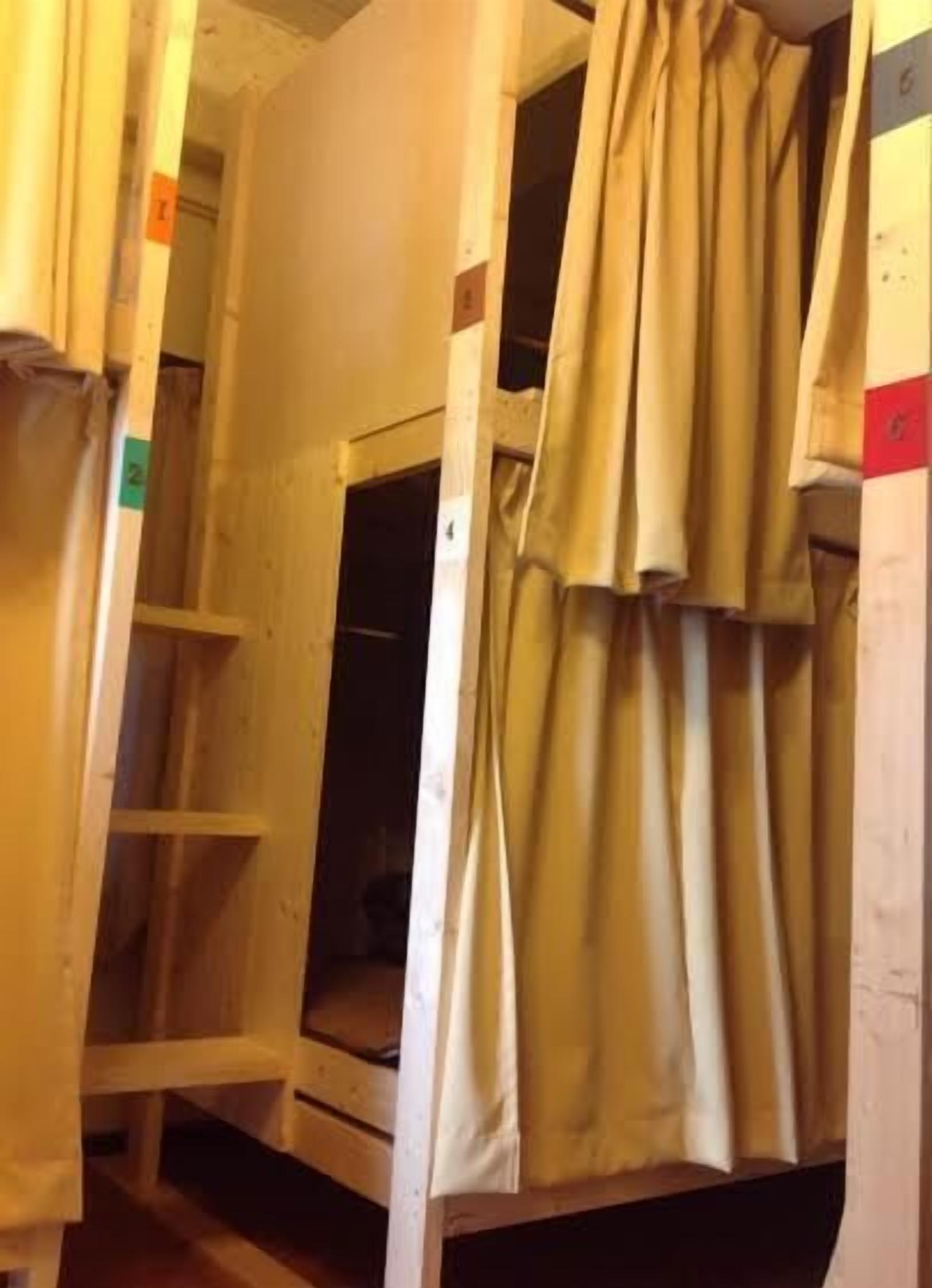 A bunk bed room with a curtain, wooden walls, and a small window.
