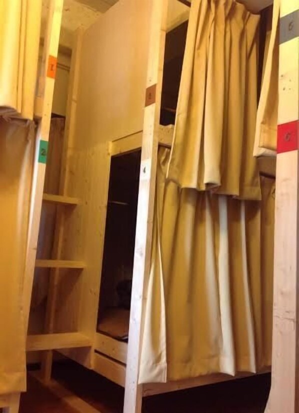 A bunk bed room with a curtain, wooden walls, and a small window.