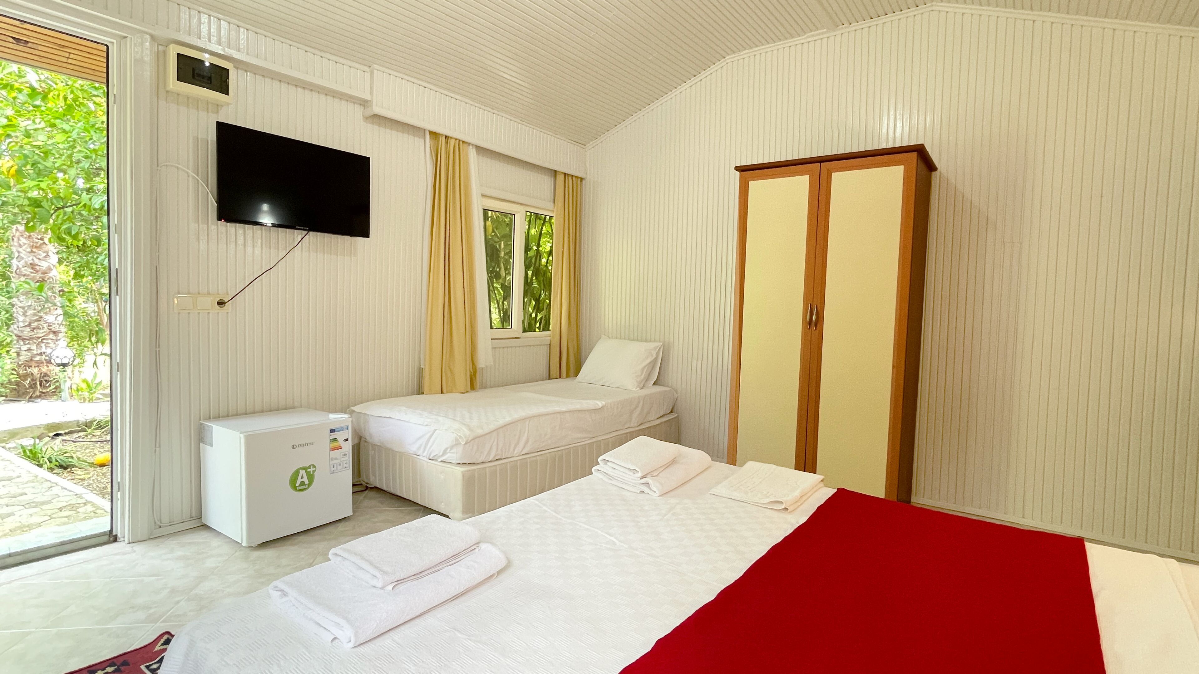 A bedroom with a bed, a TV, a small desk, and a wardrobe.