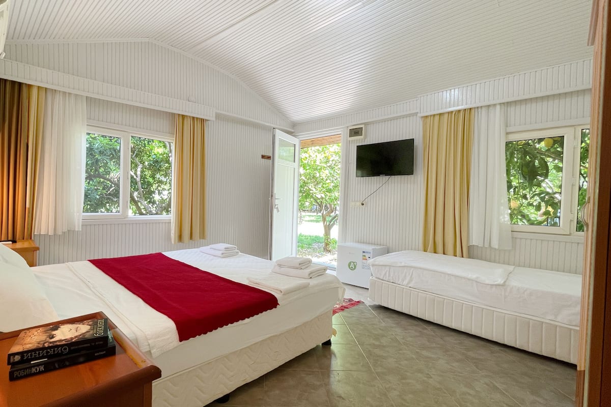 A hotel room with two beds, a TV, and a window with curtains.