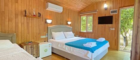 Una habitación con paneles de madera, una cama, una mesita de noche y un pequeño armario blanco.