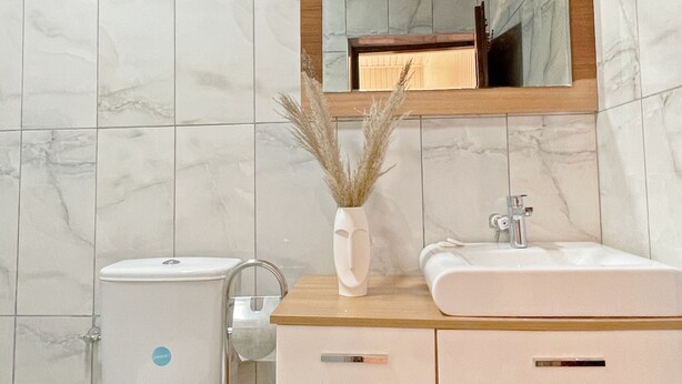 Un bagno con piastrelle bianche, un mobile lavabo in legno, un water e uno specchio.