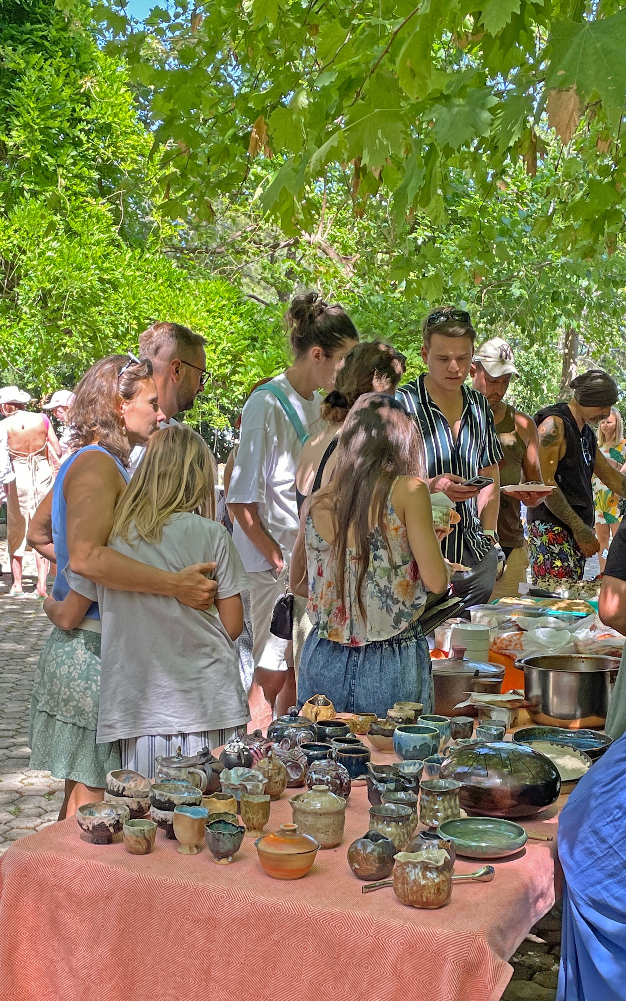 A group of people gathered around a table displaying various ceramic items.