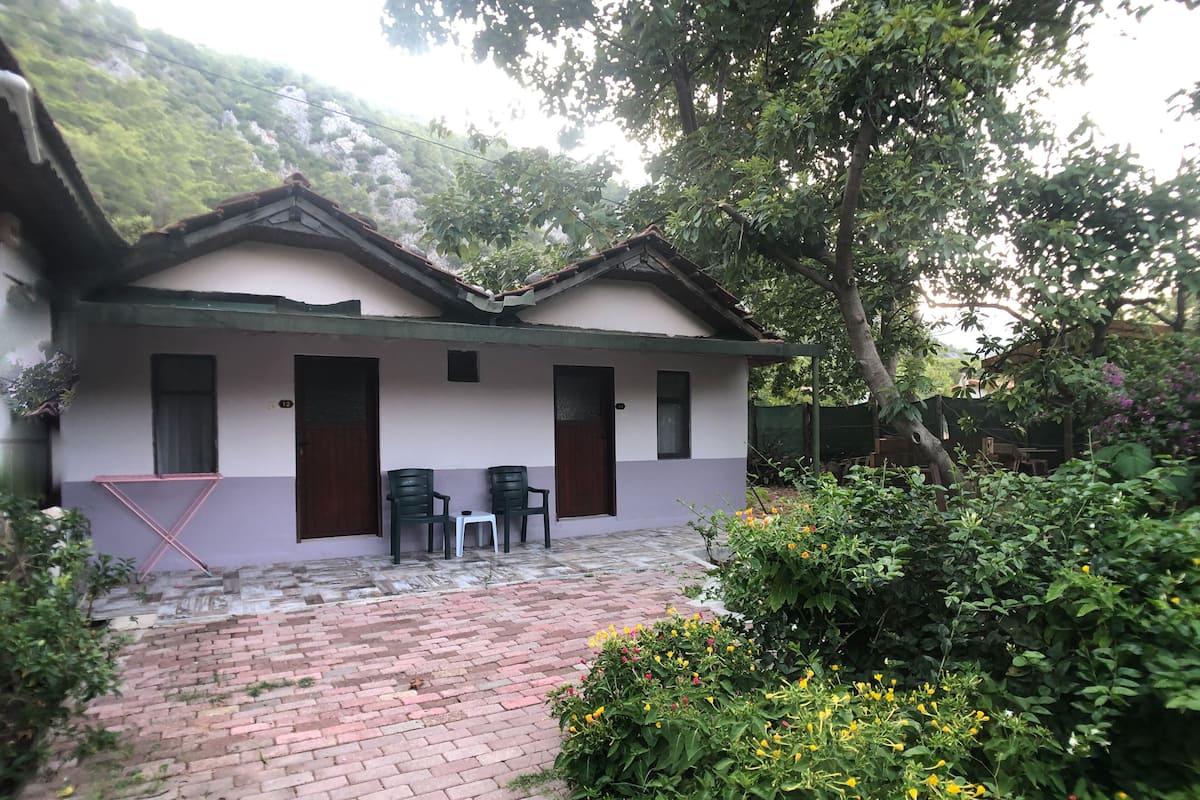 A two-story building with a brick pathway leading to a covered patio area. There are two chairs and a small table on the patio.