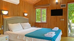Ett hotellrum med en säng, en tv, ett fönster och en väggmonterad luftkonditioneringsanläggning.