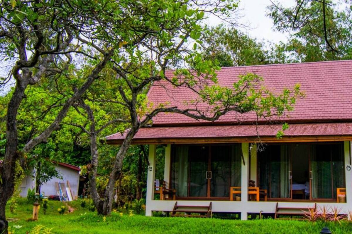 A house with a red roof, large windows, and a porch with wooden furniture.