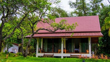 Ein Haus mit rotem Dach, großen Fenstern und einer Veranda mit Holzmöbeln.