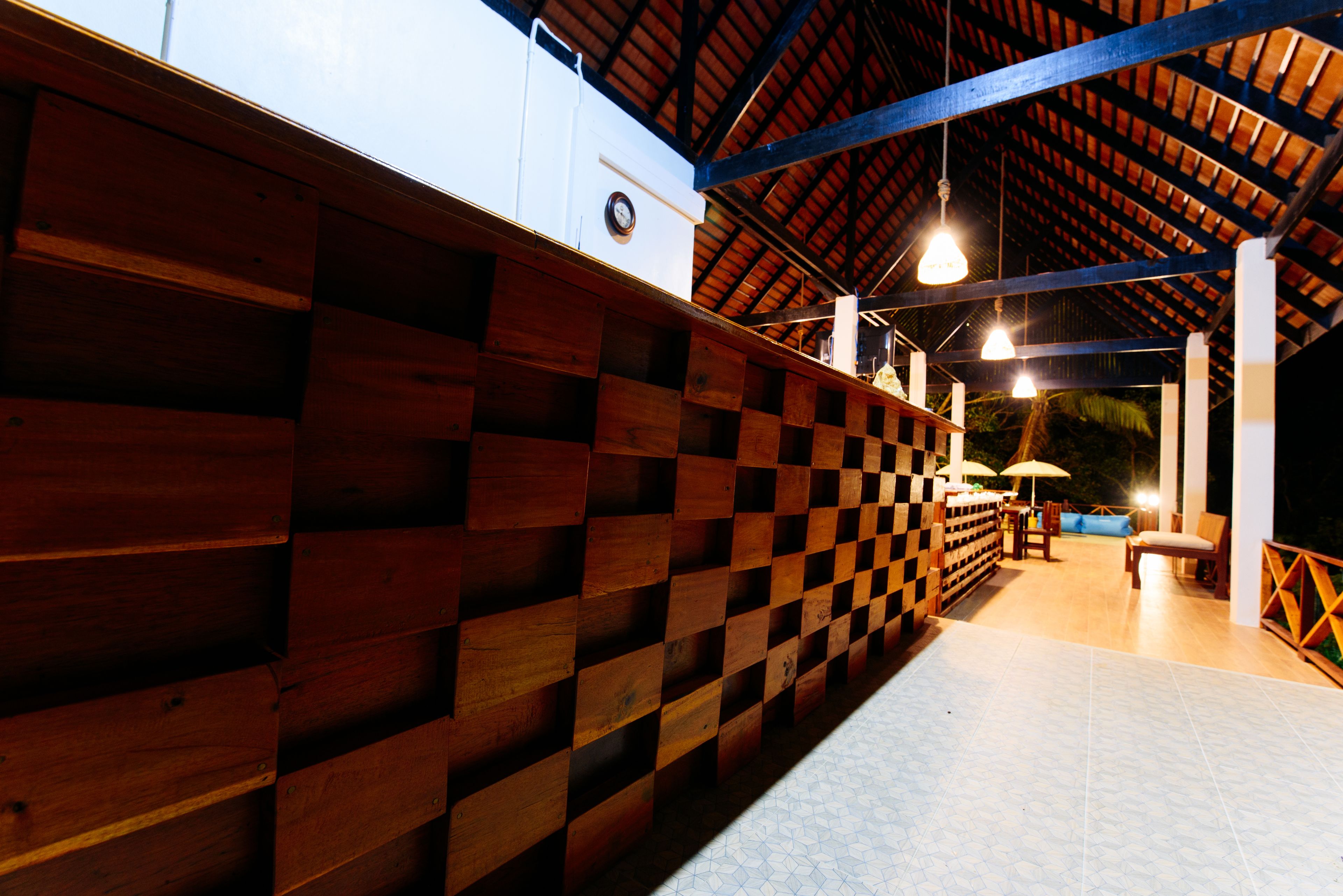 A wooden wall with a checkered pattern, a ceiling with exposed beams, and a tiled floor.