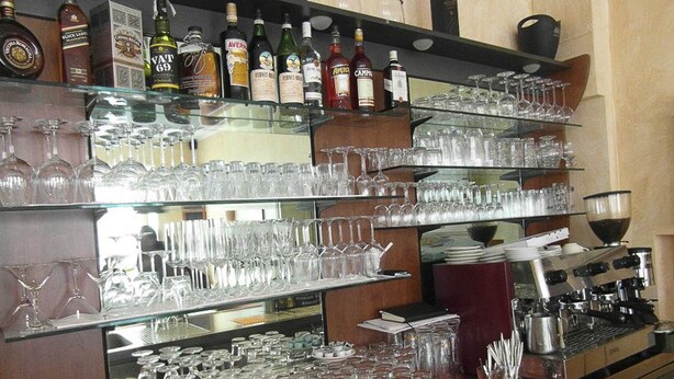 A bar area with shelves of liquor bottles and a variety of glasses. - Mantra Gästehaus (Dachau)