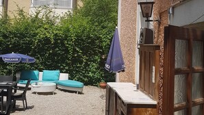 A courtyard with outdoor seating, a wooden cabinet, and a door. - Mantra Gästehaus (Dachau)