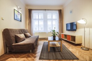A cozy living room with a sofa, a coffee table, a TV, and a floor lamp. - Accommodation Smečky 14 (Prague)