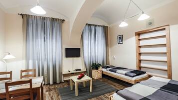 Una habitación con cama, escritorio, silla, televisor y cortinas.