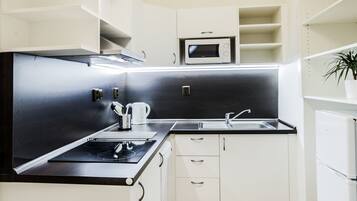 A modern kitchen with white cabinetry, a black countertop, and a microwave.