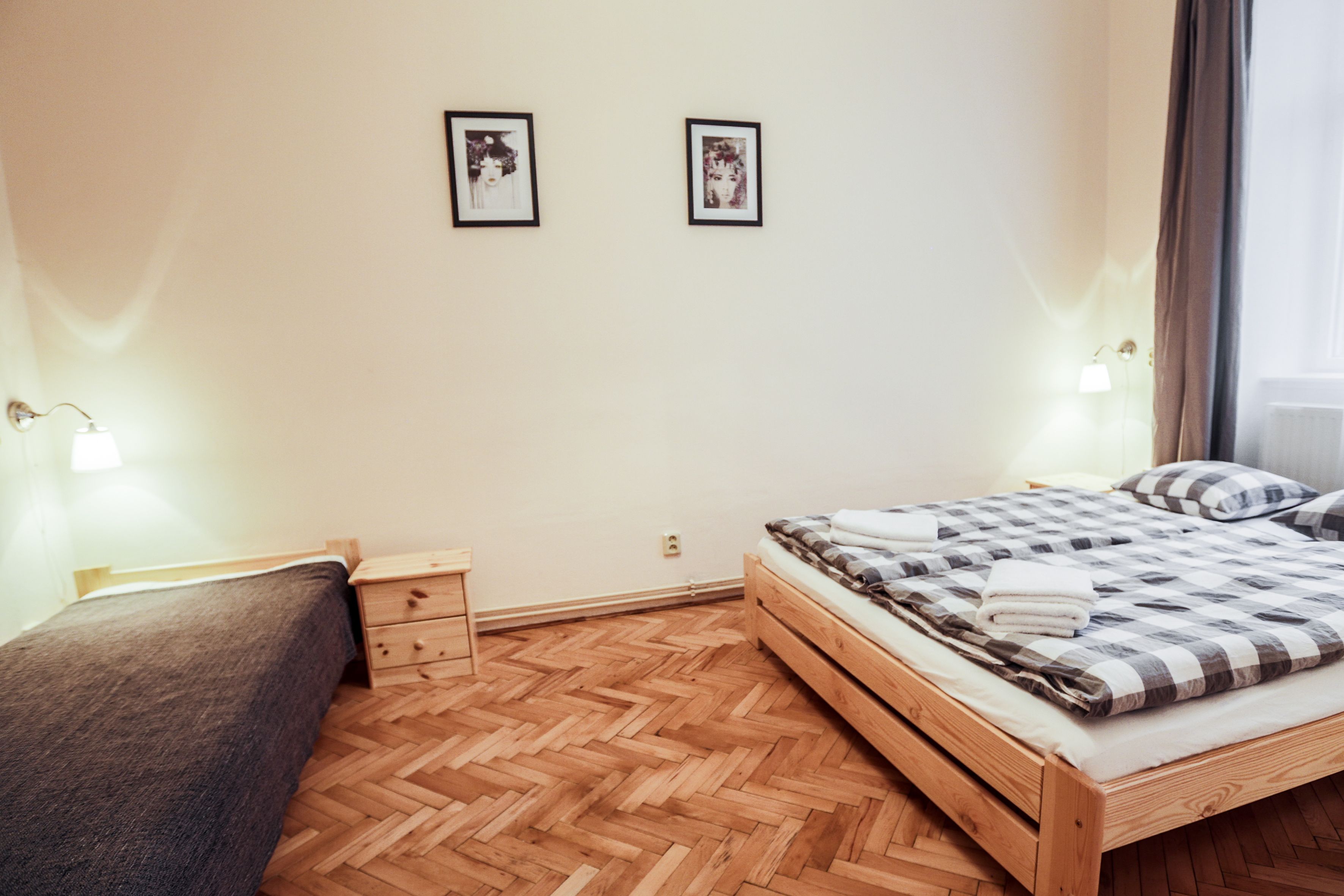 Une chambre à coucher avec un lit en bois, une table de chevet, une commode et deux lampes fixées au mur.