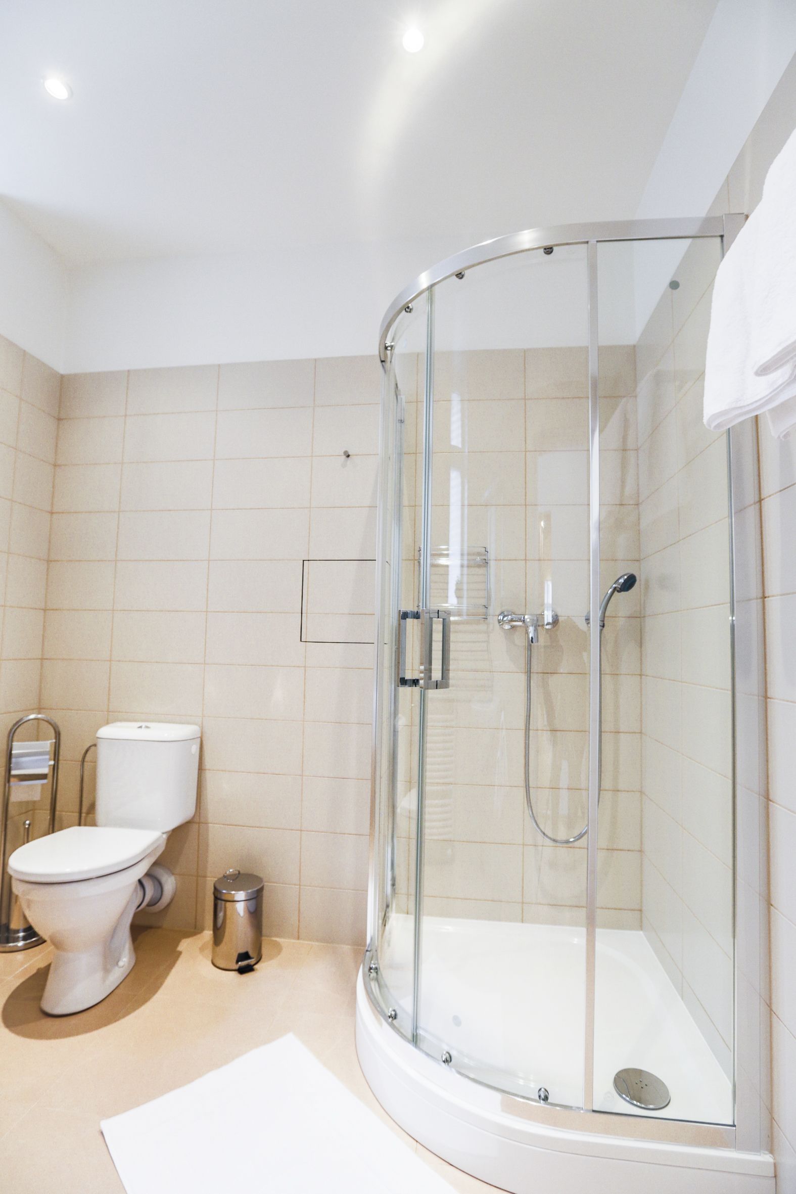 Un baño moderno con ducha de mampara de vidrio, inodoro y un cubo de basura.