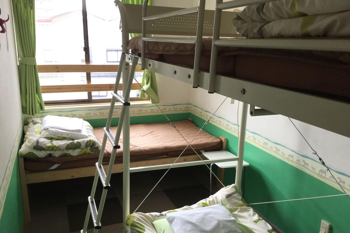 A bunk bed room with green walls, a window with curtains, and a ladder.