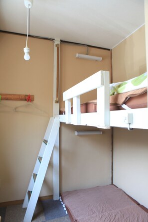 Habitación con literas, una escalera, una lámpara colgante y un perchero de madera.