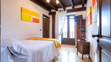 Un dormitorio con cama, mesita de noche, armario y puerta que da a un balcón.