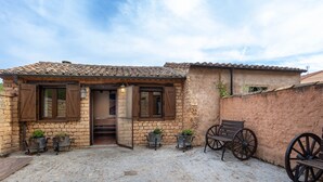 A rustic stone building with a tiled roof, wooden shutters, and a cobblestone courtyard. - Casa Rural Casa Adolfo (Santa Inés)