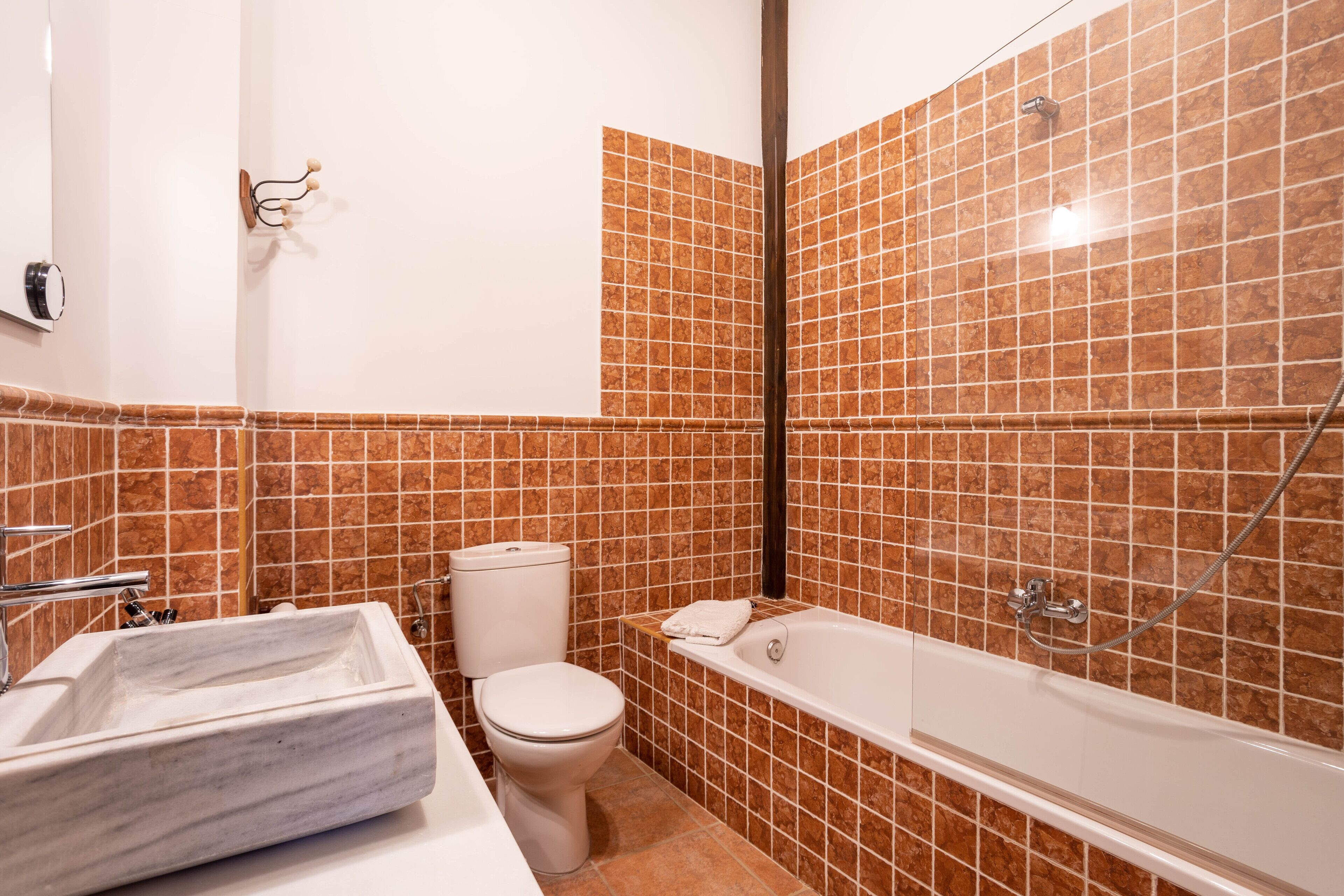 Un baño con lavamanos, inodoro y bañera con ducha de mármol.