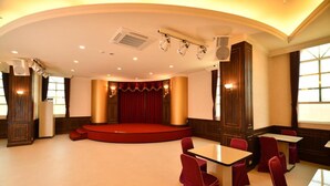 A conference room with a stage, red curtains, and a seating arrangement. - Chuan Cheng Castle Hotel (Magong)