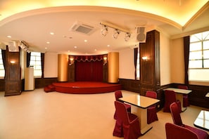 A conference room with a stage, red curtains, and a seating arrangement. - Chuan Cheng Castle Hotel (Magong)