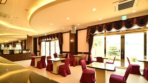 Una sala conferenze con tavoli e sedie, un'area bar e ampie finestre con tende.
