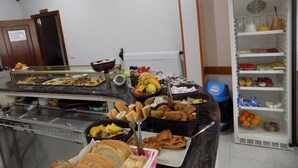 A buffet area with various food items, including bread, pastries, fruits, and beverages. - Hotel Arenal (Fisterra)