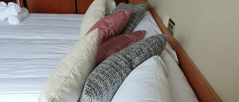 A neatly made bed with white and patterned pillows, a wooden headboard, and a framed picture on the wall.