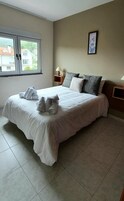 Una cama bien hecha con toallas, una mesita de noche con una lámpara y un cuadro en la pared.
