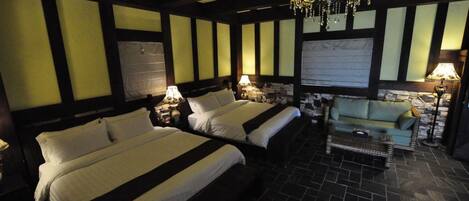 Une chambre d’hôtel avec deux lits, un lustre, un canapé et un sol carrelé.