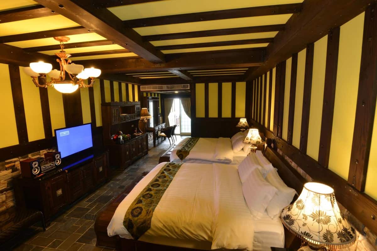 A hotel room with a large bed, a TV, and a wooden ceiling.
