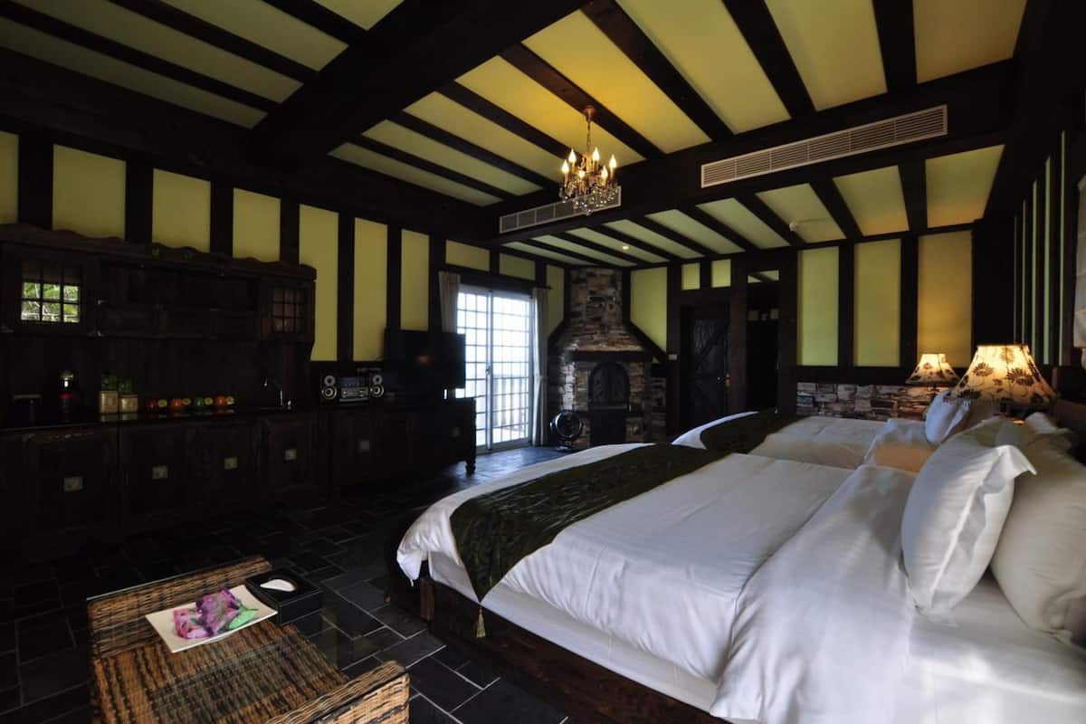 A large, well-appointed bedroom with a stone fireplace, a chandelier, and a large bed with multiple pillows.