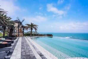 A beachfront hotel with a windmill, infinity pool, and palm trees. - Stuart Villa (Shoufeng)