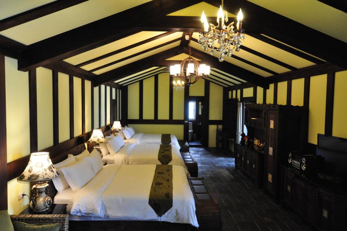 A room with two beds, a chandelier, and a television.
