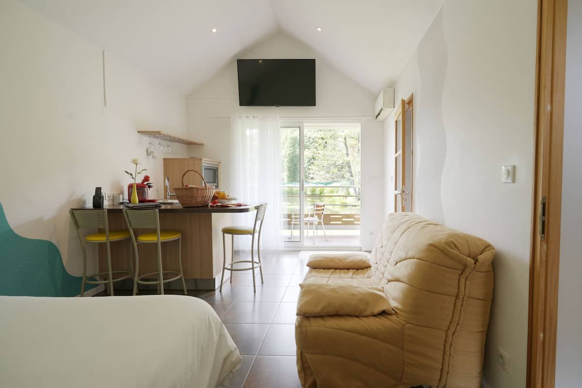 Una habitación compacta con kitchenette, sofá y comedor con sillas.