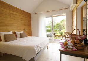 A bedroom with a large bed, a breakfast table with pastries, and a view of the outdoors. - Hôtel Sans Val'Eau (Froideterre)