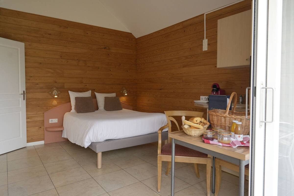 Un dormitorio con cama, lámparas de noche, una mesa con cosas para el desayuno y una puerta.