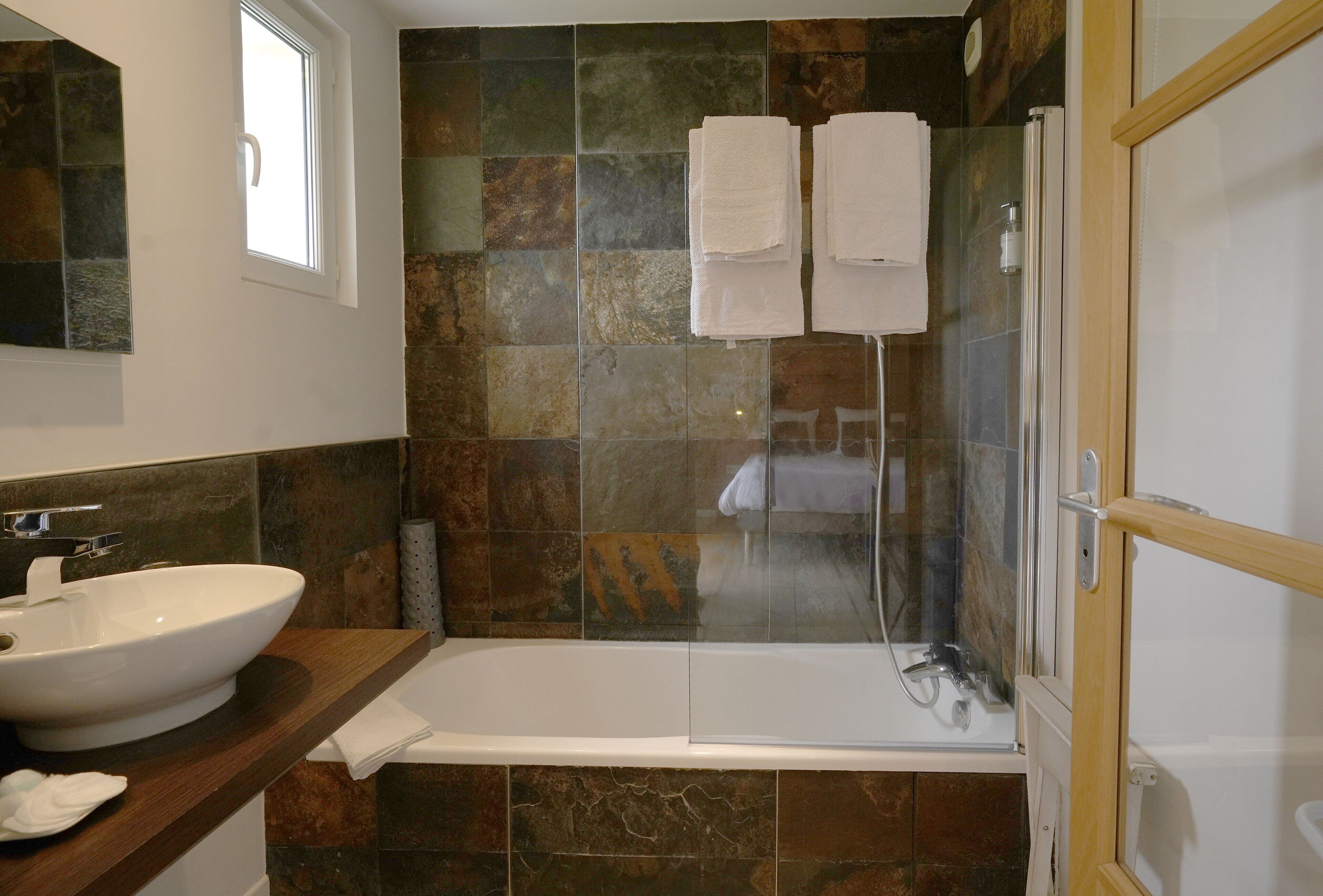 A bathroom with a bathtub, a sink, and a glass shower enclosure.