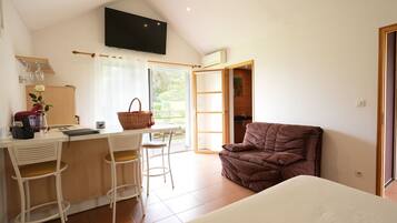 A modern room with a kitchenette, a dining area with bar stools, a brown sofa, and a large bed.